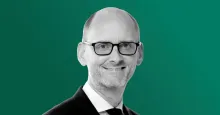 A black-and-white headshot photograph of Apollo chief economist Torsten Slok in a suit and glasses against a green background.