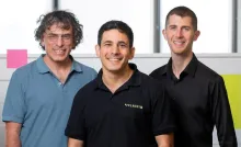 The three co-founders of quantum software company Classiq posing together in an office, one wearing a Classiq polo shirt.