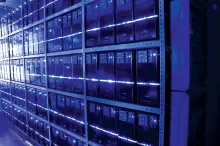 Rows of servers fill a data centre room, lit in blue, of the kind planned for large-scale AI training and inference workloads.