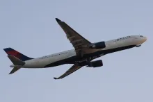 A Delta Air Lines Airbus A330 climbs into a clear sky shortly after takeoff.