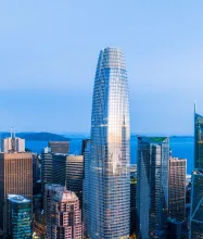A photograph of Salesforce Tower rising above the downtown San Francisco skyline at dusk.