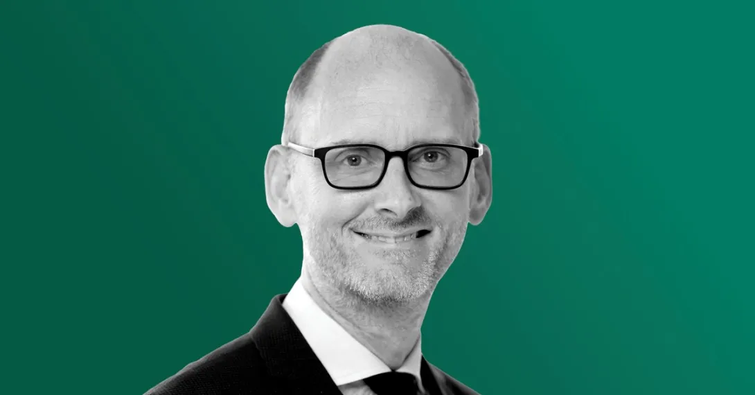 A black-and-white headshot photograph of Apollo chief economist Torsten Slok in a suit and glasses against a green background.