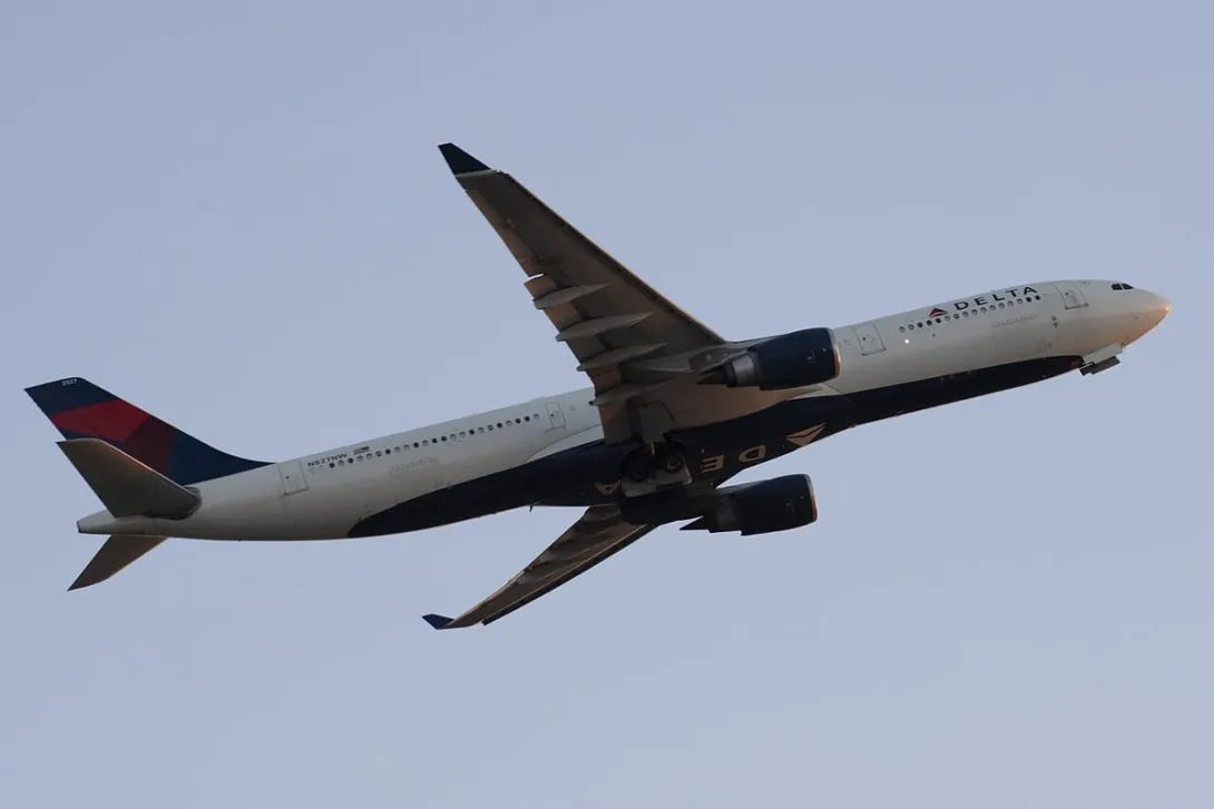 A Delta Air Lines Airbus A330 climbs into a clear sky shortly after takeoff.